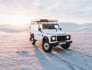 Land Rover parked on dunes at sunset