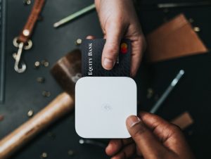 Equity credit card with hand inserting into payment Square