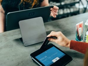 A hand inserting a credit card into a credit card machine