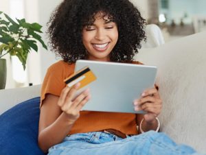 Woman smiling holding a tablet and credit card