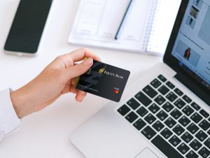 Hand holding an Equity Bank Credit card next to a laptop
