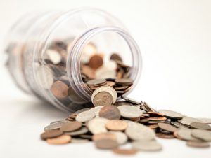 A jar of change on its side with coins spilling out.