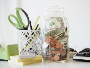 A jar of money and change on a desk