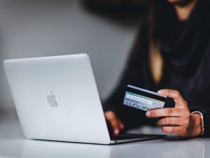 Hand holding credit card in front of laptop