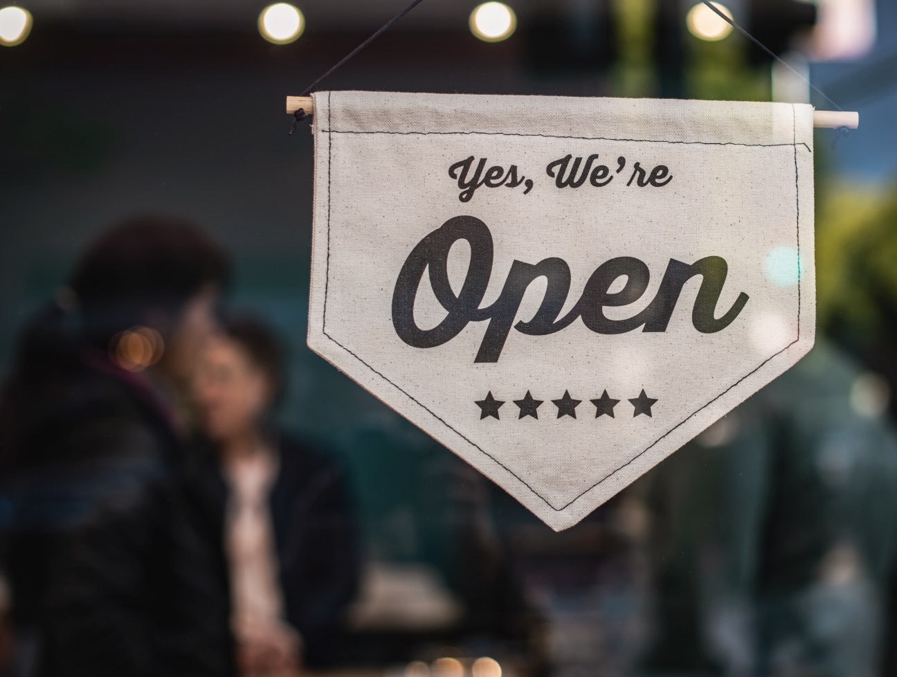A 'We're Open' flag sign hanging in store window
