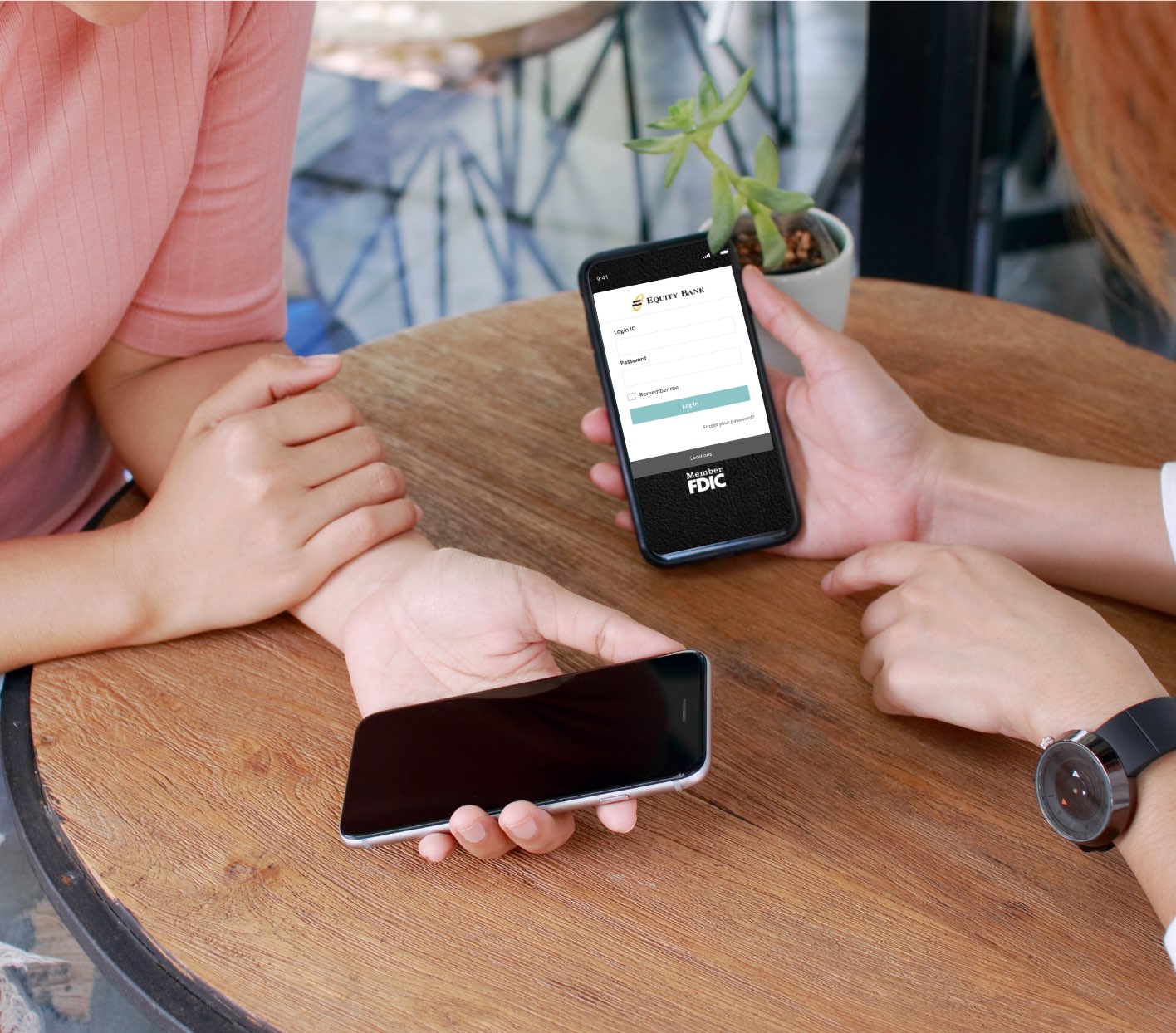 Two people holding phones over a table using the banking app