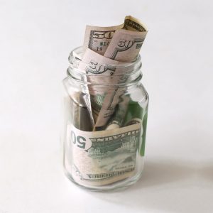 A clear glass jar full of money bills