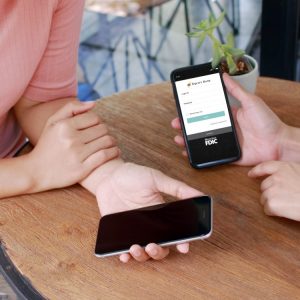Two sets of hands holding phones with the Equity Bank app at a table