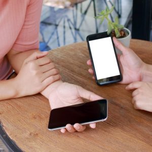 Two sets of hands holding phones at a table