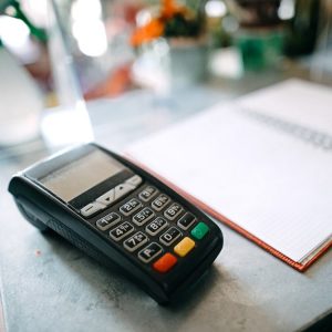 A credit card machine and notebook on a countertop