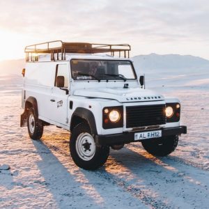 Land Rover parked on dunes at sunset