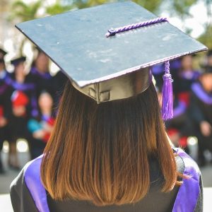 Back view of female student wearing graduation cap and gown