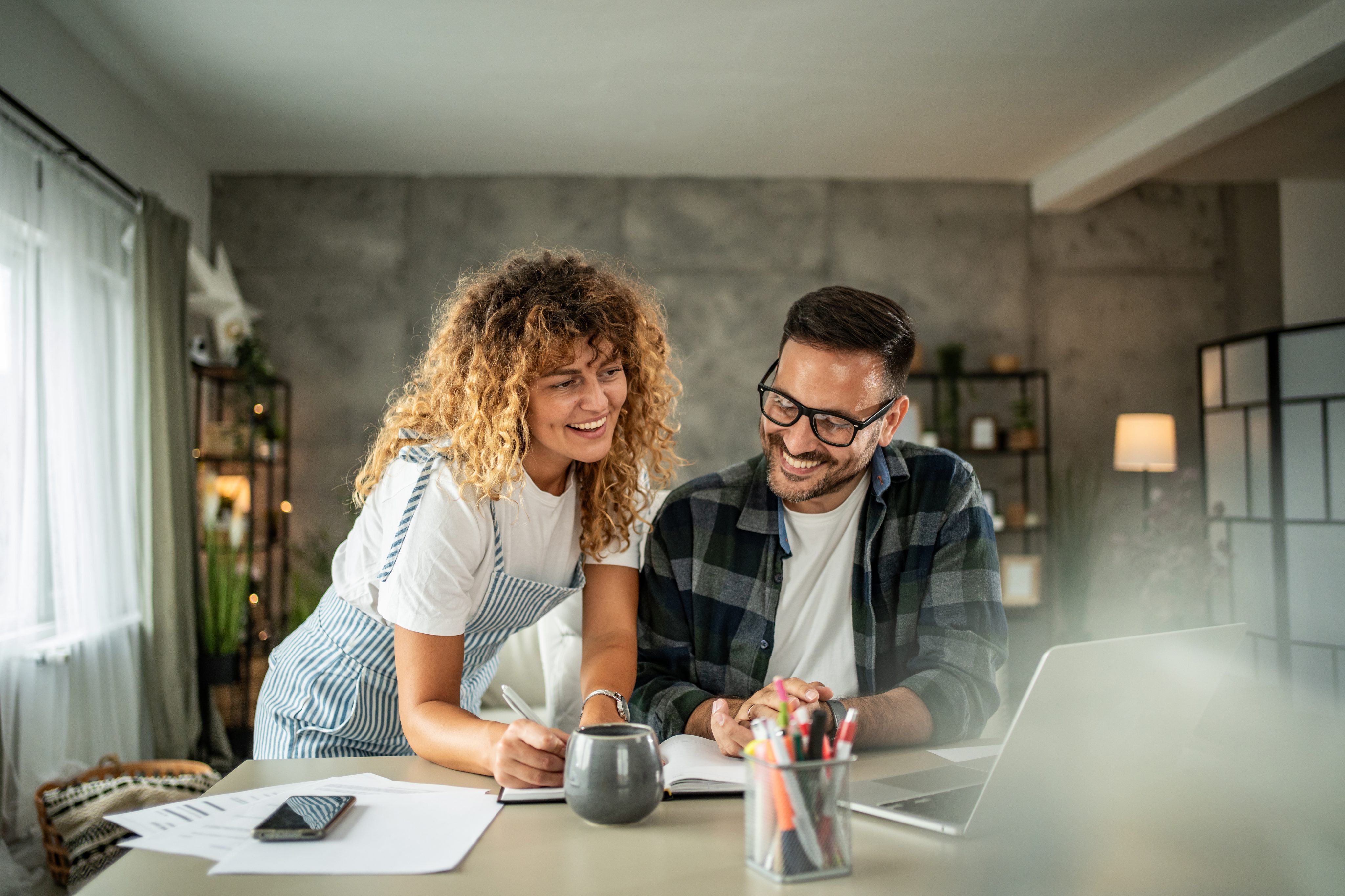 Couple reviewing finances together at home using a laptop and notebook to plan savings and investment goals