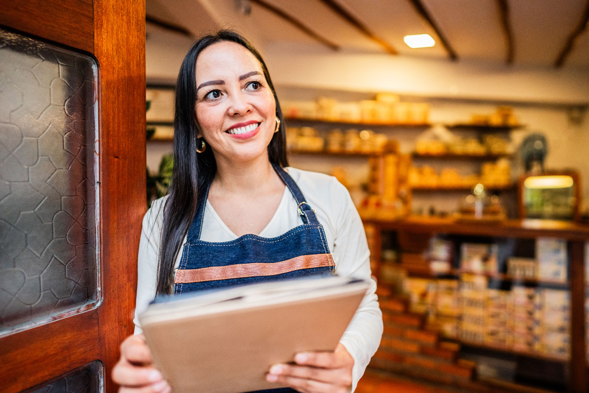 Business owner holder papers looking out her front door.