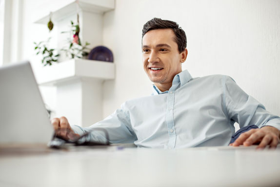 Professional in a nice home doing business banking on his laptop.