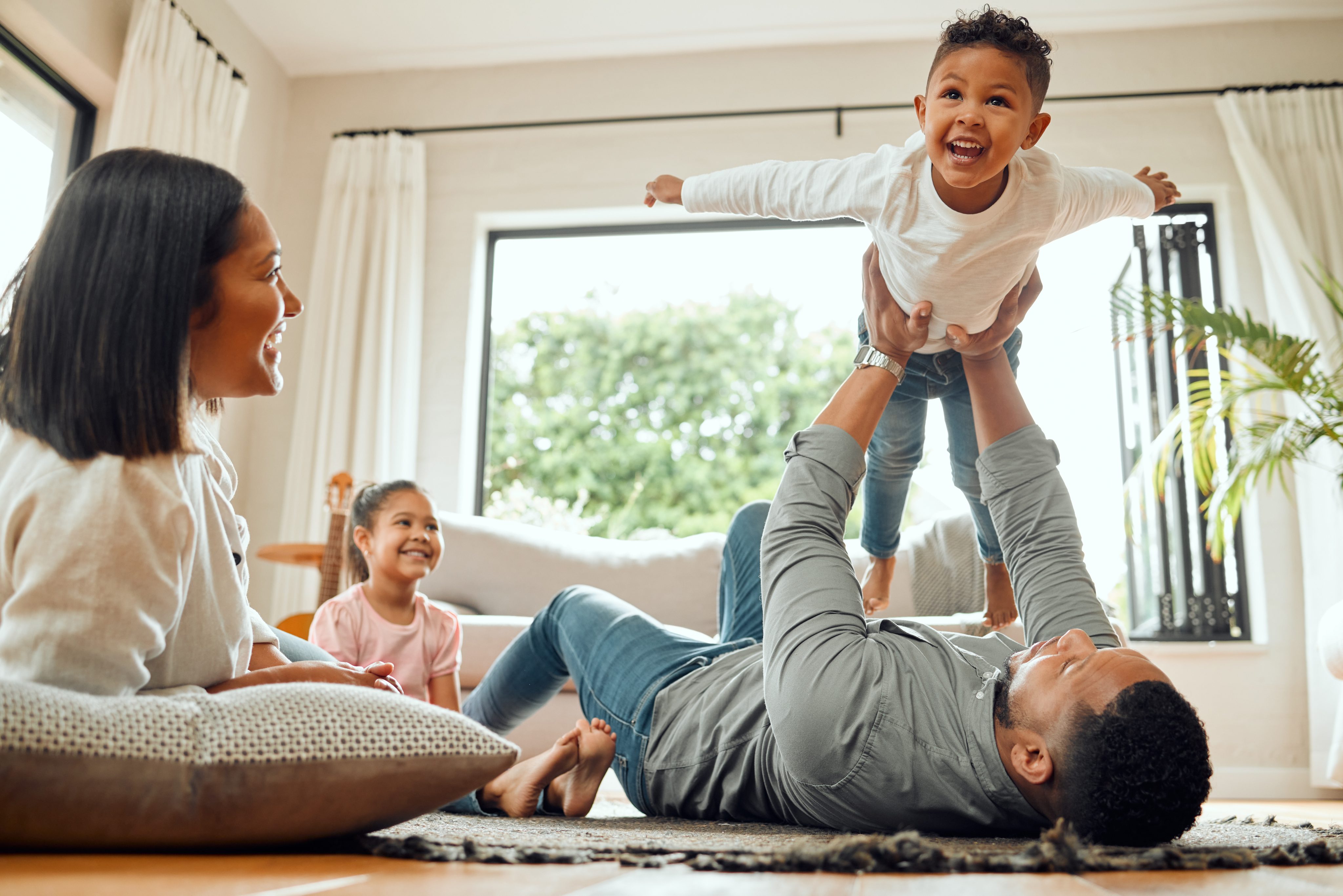 A mother and father playing with a young child in a living space