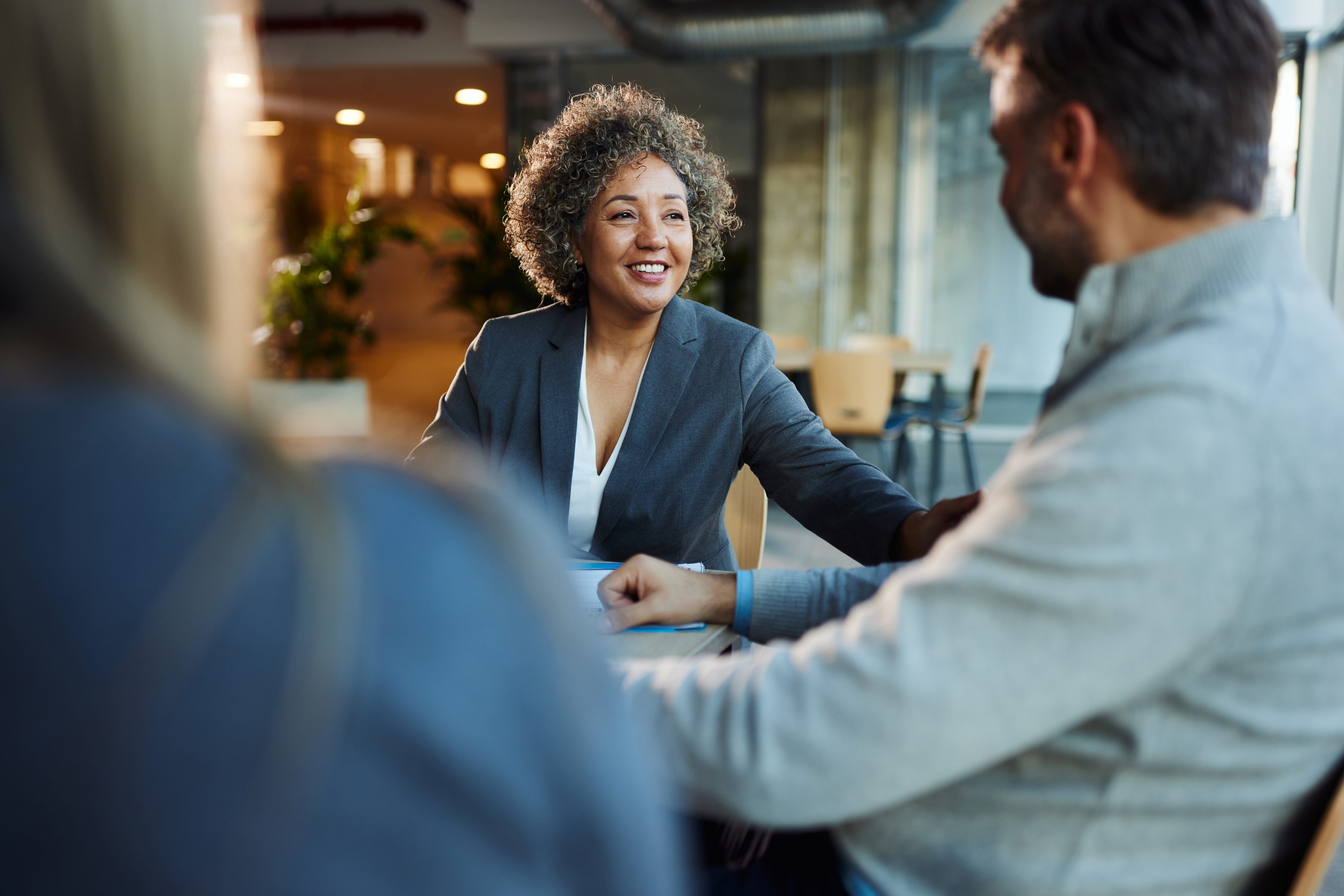 An Equity Bank financial advisor smiling and discussing personalized retention strategies with a couple in a modern office setting.